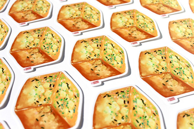 May include: A collection of stickers featuring a detailed illustration of a piece of garlic bread. The bread is golden brown with green and black toppings, set against a white background.