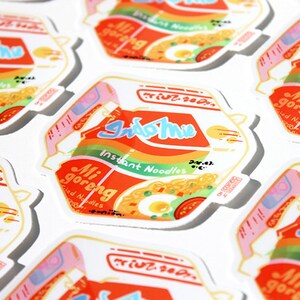 May include: A collection of colorful stickers featuring the Indomie Mi Goreng instant noodle brand. The stickers are printed with the brand's logo, product name, and a depiction of the noodles. The stickers are perfect for adding a touch of fun and personality to laptops, water bottles, or other surfaces.