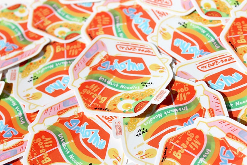 May include: A pile of colorful stickers featuring the Indomie brand of instant noodles. The stickers are designed to look like the Indomie packaging, with the brand name and product name in a stylized font. The stickers are a fun and quirky way to show your love for Indomie.