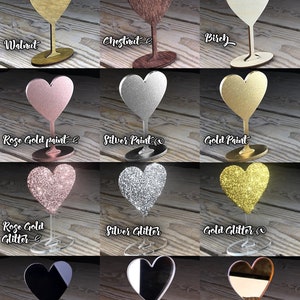 May include: Color chart showing different finishes for heart-shaped acrylic place card holders. Options include walnut, chestnut, birch, rose gold paint, silver paint, gold paint, rose gold glitter, silver glitter, gold glitter, black acrylic, silver mirror acrylic, and gold mirror acrylic.