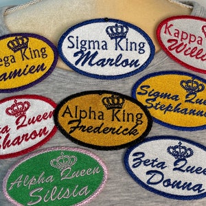 May include: Nine oval-shaped embroidered patches with a crown design and names. The patches are in various colors, including red, white, blue, yellow, green, and black. The names on the patches include "Omega King Damien", "Sigma King Marlon", "Kappa King William", "Sigma Queen Stephannie", "Delta Queen Sharon", "Alpha King Frederick", "Alpha Queen Silisia", and "Zeta Queen Donna".