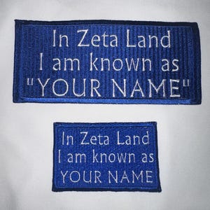 May include: Two blue embroidered patches with white text. The top patch reads "In Zeta Land I am known as "YOUR NAME"". The bottom patch reads "In Zeta Land I am known as YOUR NAME".