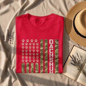Red t-shirt with a distressed American flag design featuring paw prints and the word "DACHSHUN".