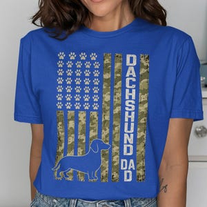 Blue t-shirt with "Dachshund Dad" text and a dachshund silhouette on a camouflage flag.