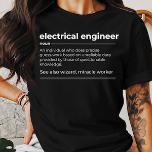 May include: Black t-shirt with white text that reads "electrical engineer noun An individual who does precise guess-work based on unreliable data provided by those of questionable knowledge. See also wizard, miracle worker"