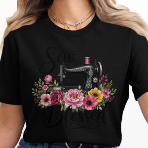 May include: Black t-shirt with a floral design and a vintage sewing machine. The design includes pink, yellow, and red flowers. The words "Sew Blessed" are written in a script font below the sewing machine.