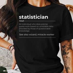 May include: A black t-shirt with white text that reads "statistician noun An individual who does precise guess-work based on unreliable data provided by those of questionable knowledge. See also wizard, miracle worker"