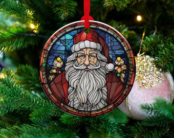 May include: A round ceramic bauble with a stained glass design of Father Christmas. He has a white beard and red hat. The bauble is decorated in blue, green and red and includes the year 2023.