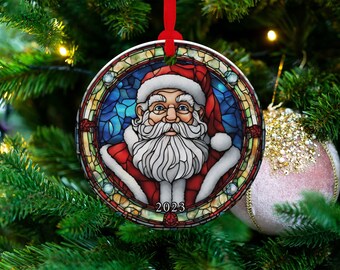 May include: A round Christmas bauble featuring a stained glass design of Santa Claus with a red hat and white beard. The bauble has a blue background with gold accents and the year 2023 printed at the bottom.