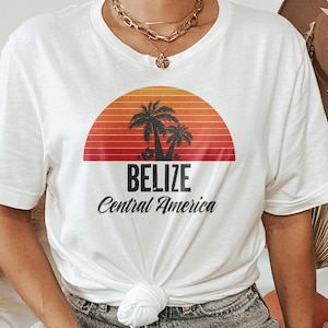 May include: White t-shirt with a graphic of a sunset over palm trees and the text "Belize Central America".