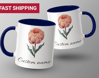 May include: Two white ceramic mugs with a blue rim and handle. Each mug features a watercolor illustration of a peach-colored flower with green leaves. The text "Custom name" is printed on the bottom of each mug.