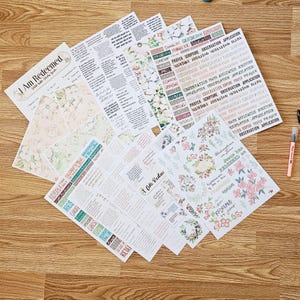 May include: A collection of paper sheets with floral designs and text. The sheets feature phrases like "I Am Redeemed" and "Prayer, Scripture, Observation, Application." The color palette includes pink, green, and beige, with handwritten-style fonts.