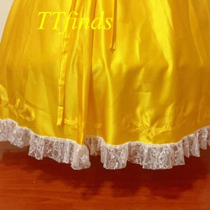 May include: A yellow satin skirt with a white lace trim. The skirt has a bow at the back and the text "TTfinds" is visible on the fabric.