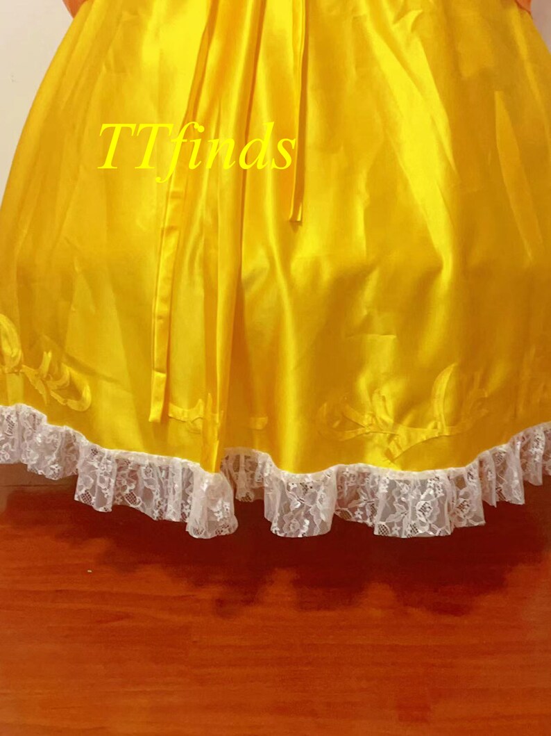 May include: A yellow satin skirt with a white lace trim. The skirt has a bow at the back and the text "TTfinds" is visible on the fabric.