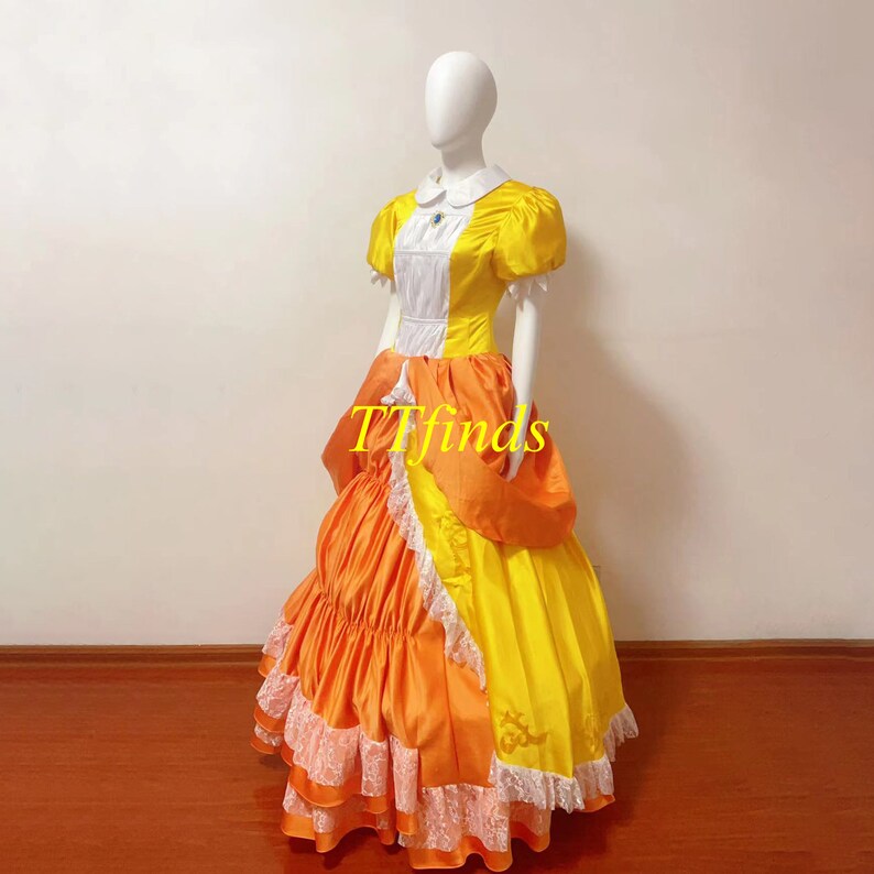 May include: A yellow and orange ball gown with a white bodice and lace trim. The dress has a full skirt and is made of satin.