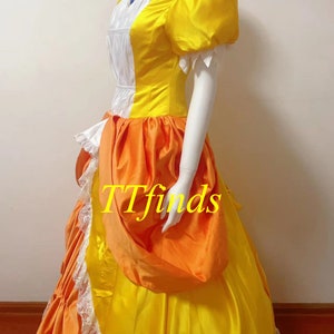May include: A yellow and orange dress with a white collar and puffed sleeves. The dress has a large orange bow on the side and a white lace trim at the bottom.