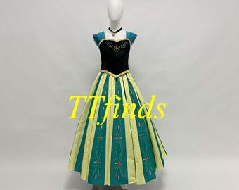 May include: A green and yellow princess dress with a black bodice and a blue and green trim. The dress has a snowflake pattern on the skirt. The dress is on a white mannequin.