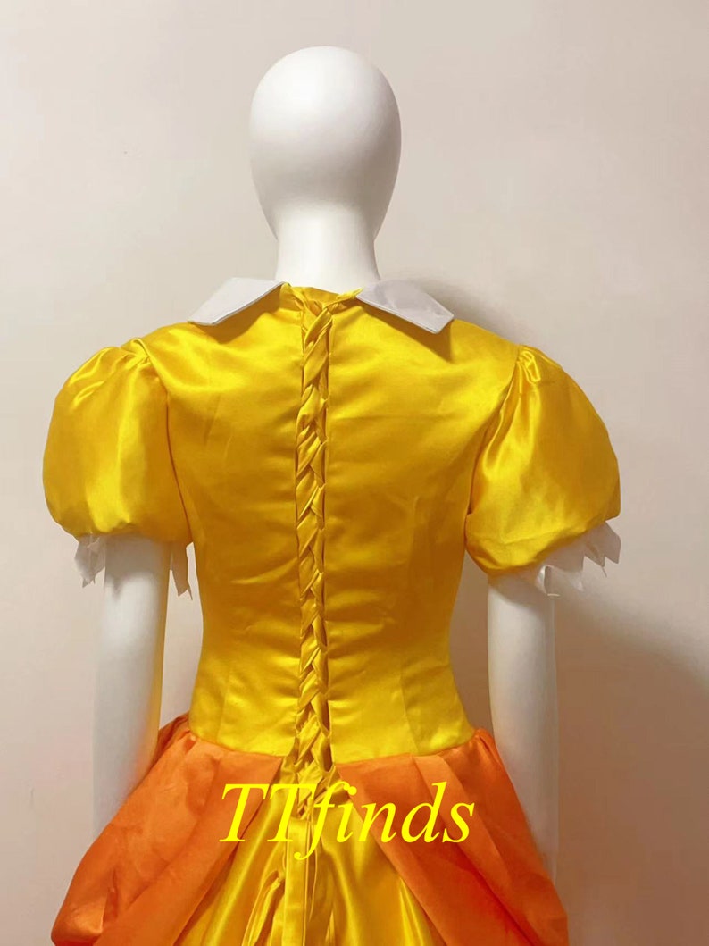May include: A yellow and orange dress with a white collar and puff sleeves. The dress has a lace-up back and a full skirt.