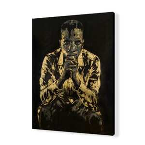 Puede incluir: Una pintura en negro y dorado de una persona sentada con las manos juntas frente a ella. La persona lleva una camisa y pantalones. El fondo es negro.