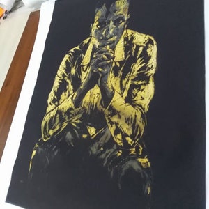 Puede incluir: Una pintura en negro y dorado de una persona sentada con las manos juntas frente a ella. La persona lleva una chaqueta y tiene una expresi&oacute;n seria en su rostro.