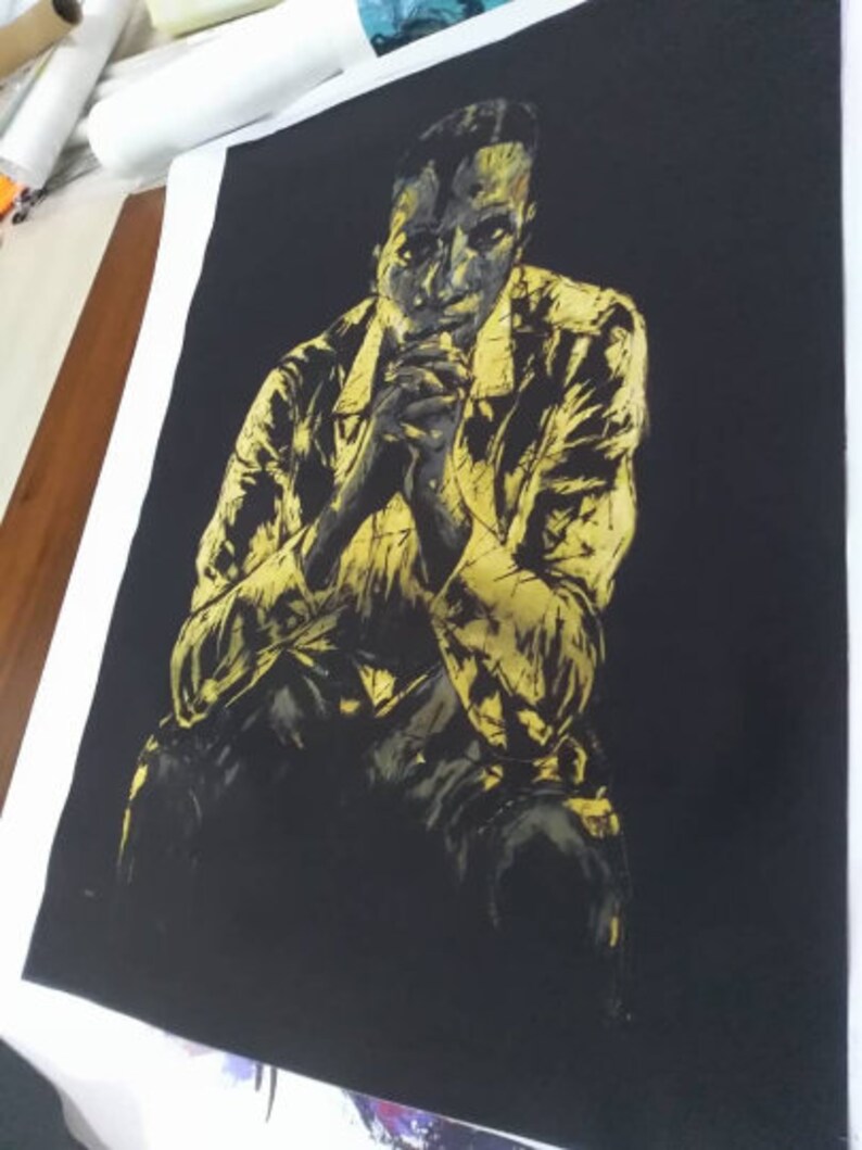 Puede incluir: Una pintura en negro y dorado de una persona sentada con las manos juntas frente a ella. La persona lleva una chaqueta y tiene una expresi&oacute;n seria en su rostro.