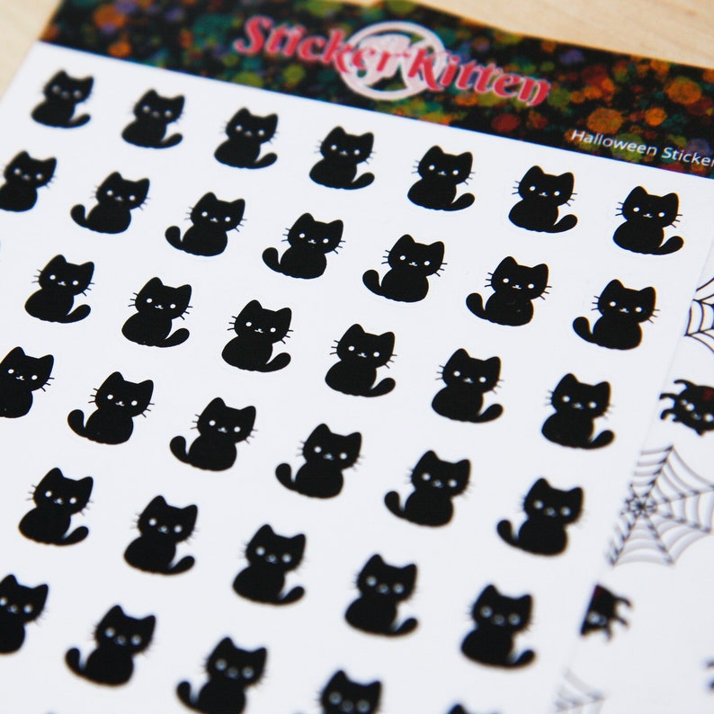 May include: A sheet of Halloween stickers featuring black cat silhouettes. The sheet is white with the text "Sticker Kitten" and "Halloween Stickers" printed on it.