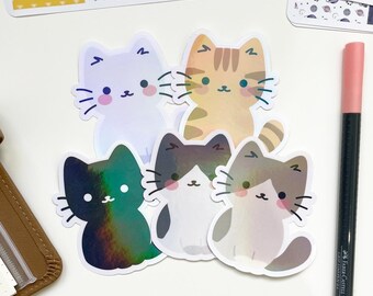 Peut inclure: Cinq autocollants de chat colorés avec différents motifs et couleurs. Les autocollants sont holographiques et ont une finition brillante. Les chats sont tous en position assise, les oreilles dressées.