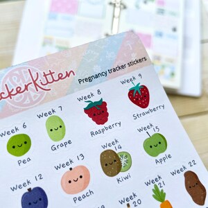 Puede incluir: Pegatinas de seguimiento del embarazo con ilustraciones de frutas lindas. Cada pegatina presenta una fruta diferente con una cara sonriente y el n&uacute;mero de semana correspondiente. Las pegatinas est&aacute;n impresas en papel blanco con un fondo colorido.