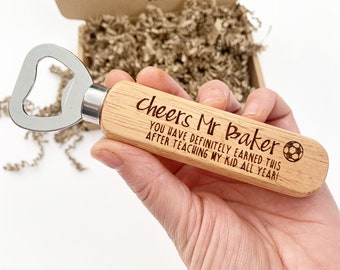 May include: Wooden bottle opener with a metal opener and a handle engraved with the text "cheers Mr Baker YOU HAVE DEFINITELY EARNED THIS AFTER TEACHING MY KID ALL YEAR!" and a soccer ball graphic.