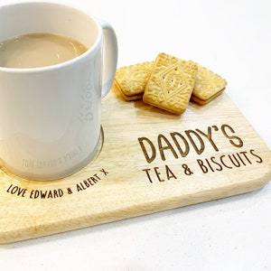May include: A wooden tray with the text "Daddy's Tea & Biscuits" engraved on it. A white mug with the text "Love Edward & Albert X" is on the tray. There are four biscuits on the tray.