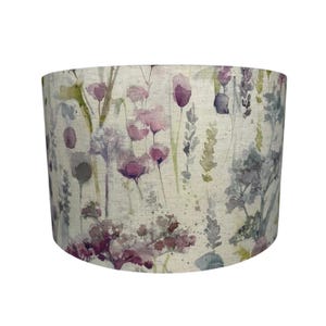 May include: Cylindrical lampshade with a watercolour floral design. The pattern features purple, pink, and green flowers and foliage on a cream background. Suitable for a table or floor lamp, it measures approximately 25 cm in height.