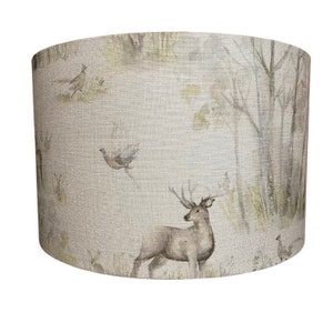 May include: A beige lampshade with a woodland scene featuring a deer, birds, and trees. The lampshade has a linen texture.