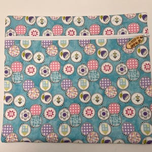 Pu&ograve; includere: Una pochette blu con cerniera, con una cerniera bianca e un'etichetta di legno che dice "Sew Much To Do". La pochette &egrave; ricoperta da un motivo di cerchi colorati con diversi disegni.