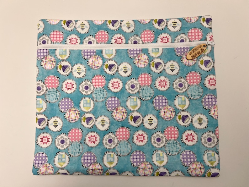 Pu&ograve; includere: Una pochette blu con cerniera, con una cerniera bianca e un'etichetta di legno che dice "Sew Much To Do". La pochette &egrave; ricoperta da un motivo di cerchi colorati con diversi disegni.