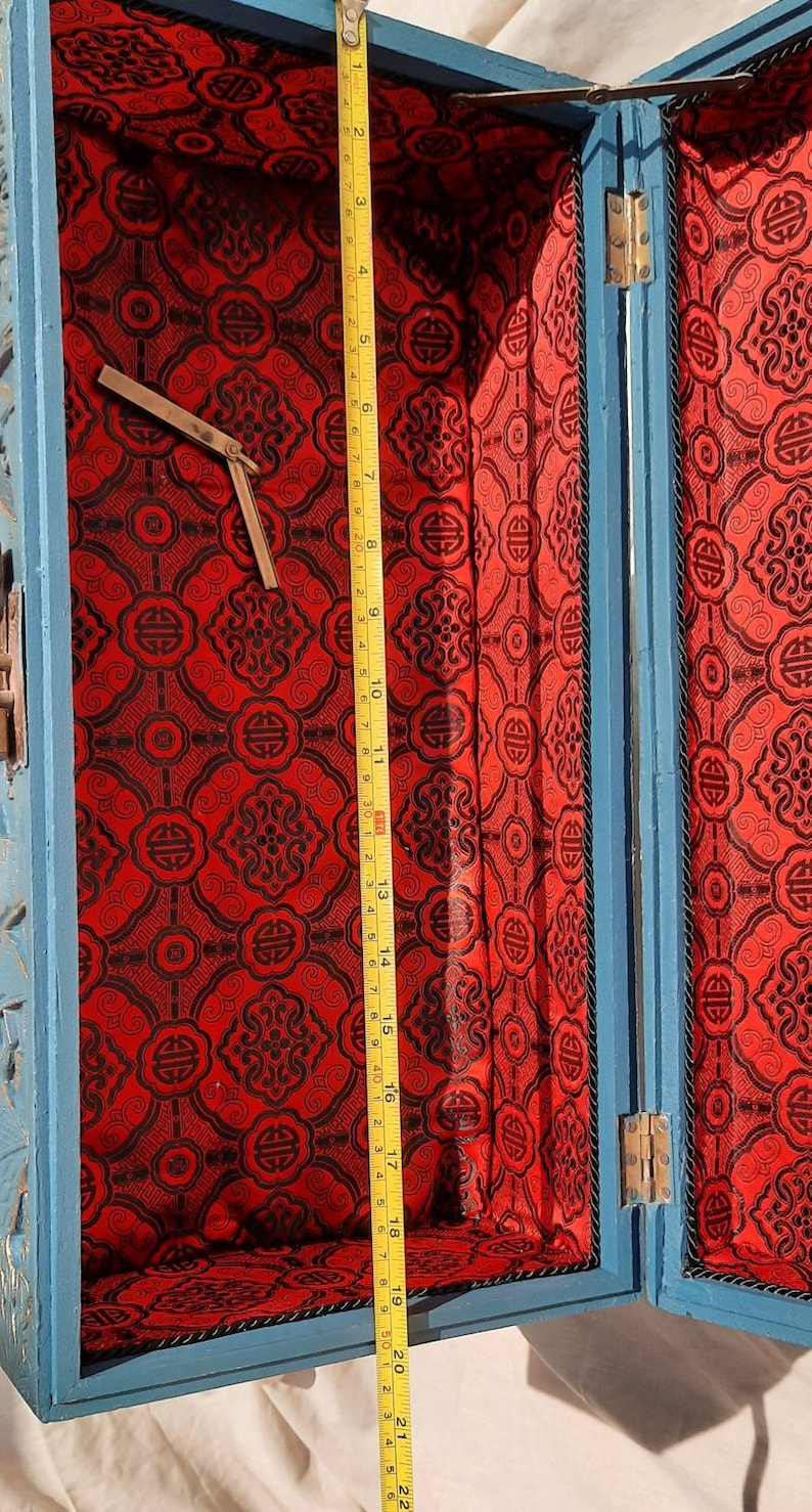 May include: A blue wooden box with a red and black patterned lining. The box is open and the lid is propped up. The box is about 20 inches long.