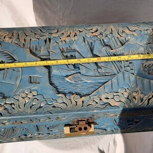 May include: A blue wooden chest with intricate carvings of a Chinese landscape scene. The chest has a brass lock and hinges. The chest is approximately 19 inches long.