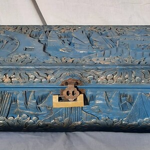 May include: A blue wooden chest with intricate carvings of ships and floral designs. The chest has a brass latch and a wooden handle.