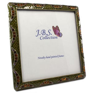 May include: Square, olive green picture frame with a textured surface and decorative jewel accents. The frame has a white interior with the text "J.B.S. Collection" and "Novelty hand painted frames". A purple butterfly graphic is also visible.