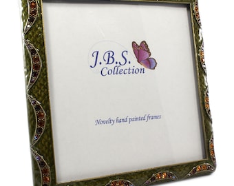 May include: Square, olive green picture frame with a textured surface and decorative jewel accents. The frame has a white interior with the text "J.B.S. Collection" and "Novelty hand painted frames". A purple butterfly graphic is also visible.