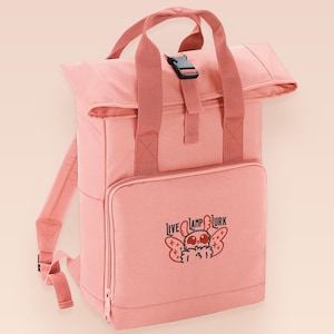 Pink roll top backpack with a front pocket and an embroided mothman cryptid design with the lext live lamp lurk