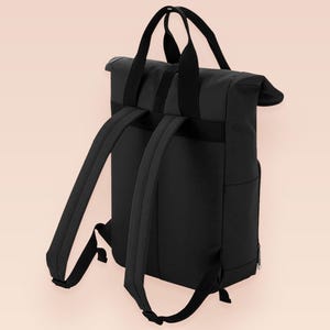 Black roll top backpack with a front pocket and an embroided mothman cryptid design with the lext live lamp lurk