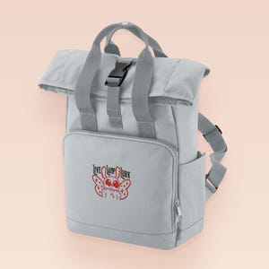 Grey roll top backpack with a front pocket and an embroided mothman cryptid design with the lext live lamp lurk