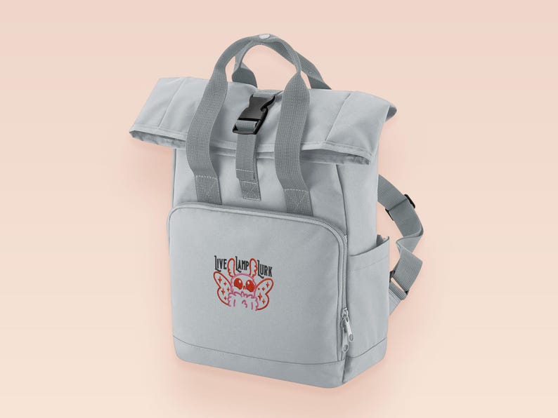 Grey roll top backpack with a front pocket and an embroided mothman cryptid design with the lext live lamp lurk