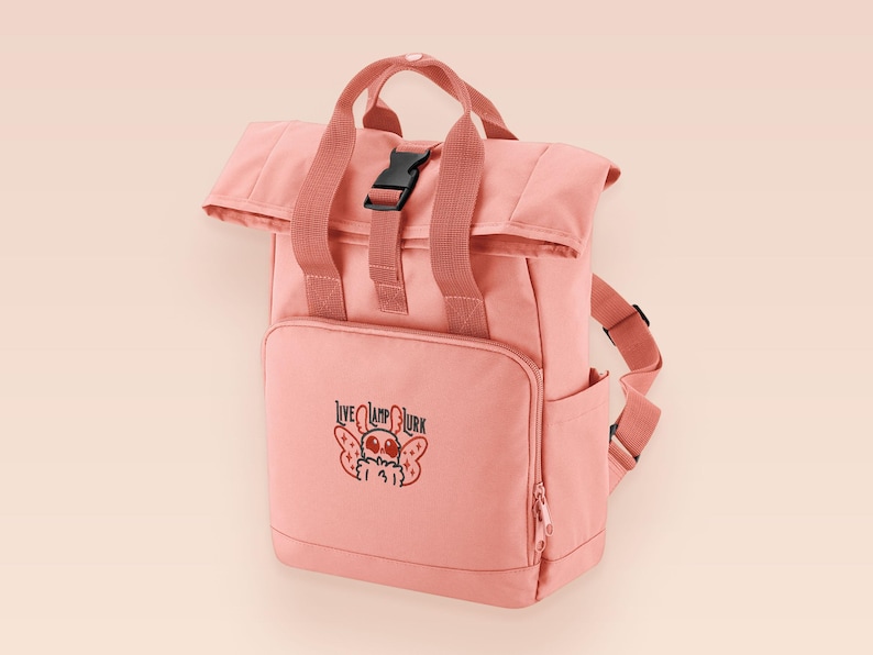 Pink roll top backpack with a front pocket and an embroided mothman cryptid design with the lext live lamp lurk