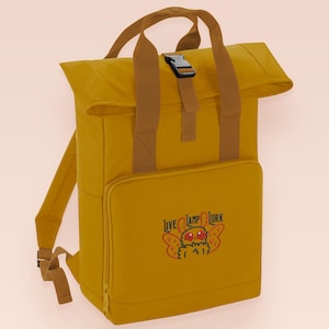 Yellow roll top backpack with a front pocket and an embroided mothman cryptid design with the lext live lamp lurk
