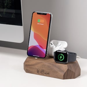 May include: A wooden charging station with a personalised name "William" engraved on the front. The station has three charging spots: one for a smartphone, one for a smartwatch, and one for wireless earbuds. The smartphone is charging and shows a 35% charge level.