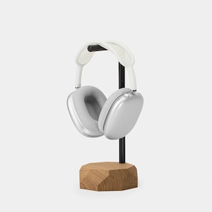 May include: Silver headphones with white earcups and a black headband, resting on a wooden stand.