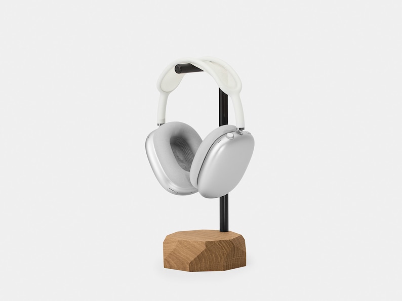 May include: Silver headphones with white earcups and a black headband, resting on a wooden stand.