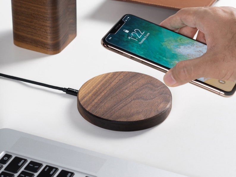 Phone being placed above a wireless charging pad on a clean desk