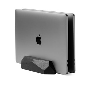 May include: A black wooden laptop stand with a geometric design. The stand is holding up two silver laptops.